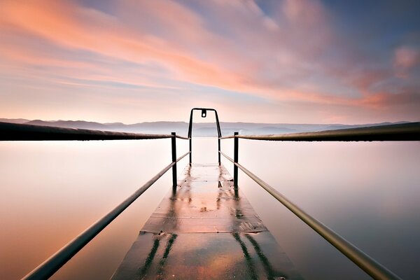 Berth on the lake on the background of pink clouds