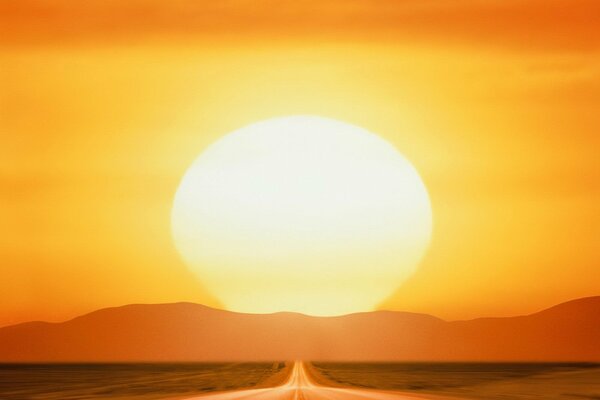 The road and the huge sun at sunset