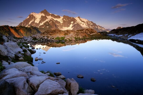 Lago azul con costa rocosa en las montañas