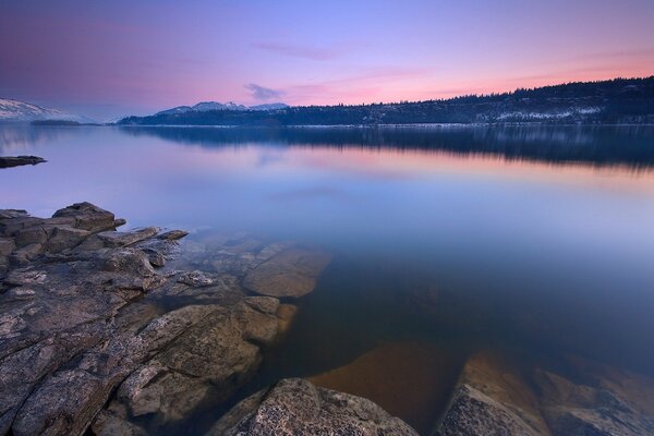 Rocky lake shore against a bright sky