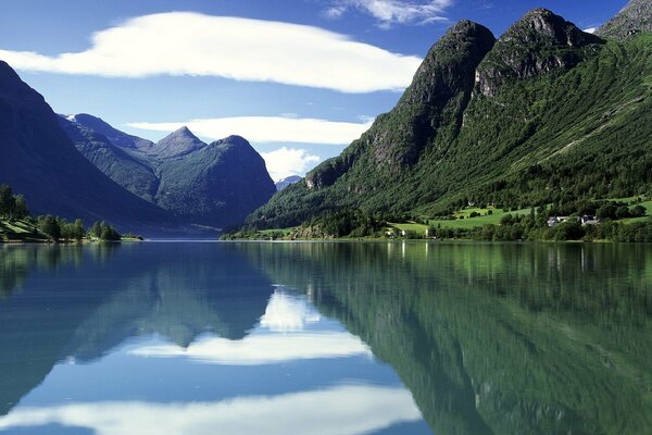 Mountains against a background of blue sky and white clouds that are reflected in the water