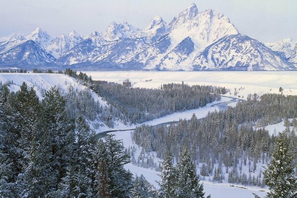 Montañas cubiertas de nieve y árboles junto al río