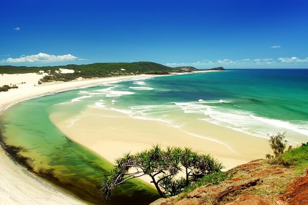 Sandy beach and sea water against a blue sky background