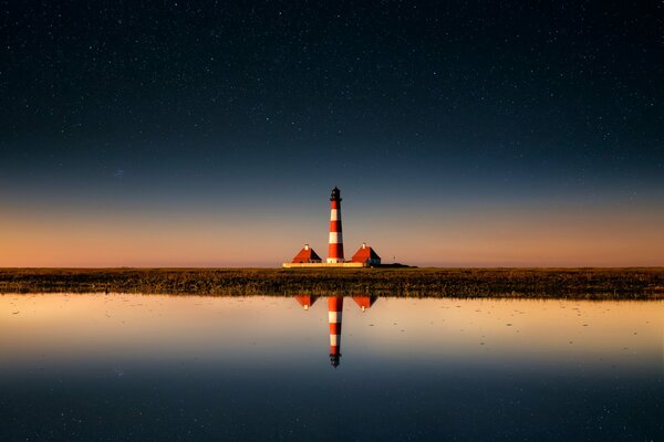 Un faro in lontananza si riflette nell acqua