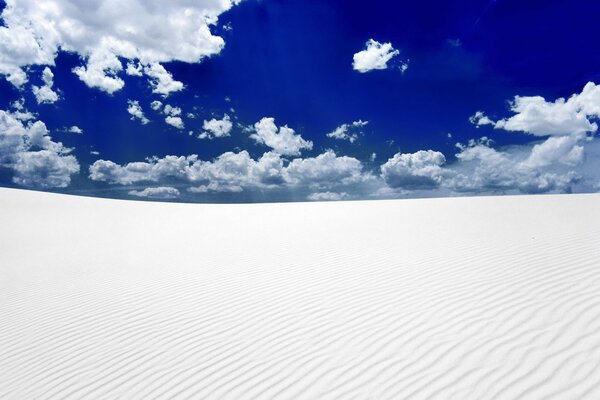 Arena blanca y cielo azul en las nubes