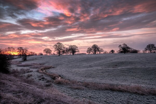 La puesta de sol llena de sombra carmesí un campo congelado