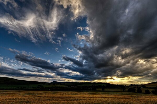 Sunrise over the field and heavy clouds