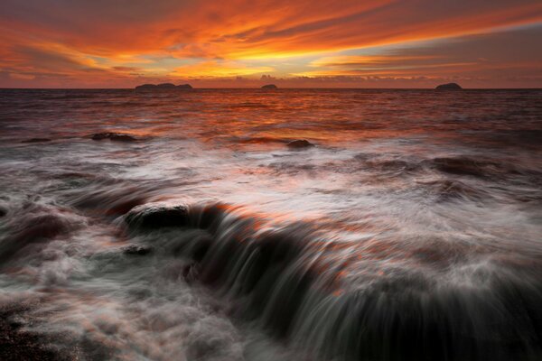 Tramonto all orizzonte con rocce di pietra vicino al mare