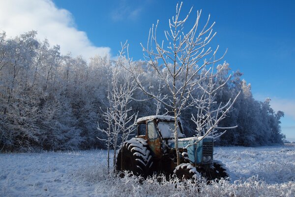 Verlassener Traktor am verschneiten Wald