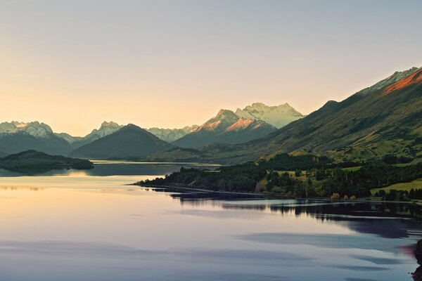 Amanecer tranquilo junto al lago con montañas