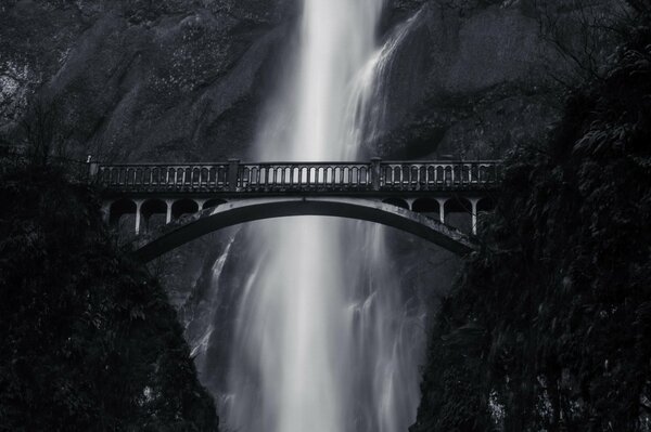 Black and white photo with bridge and waterfall