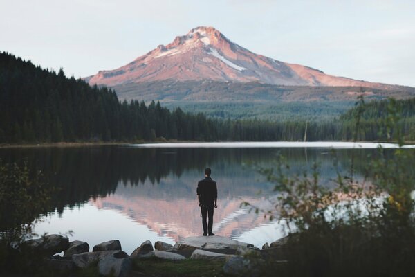 Mann auf dem Hintergrund des Sees und der Berge