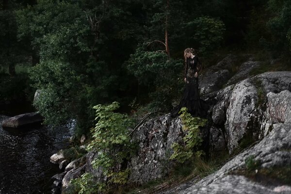 Ragazza sulle pietre sullo sfondo degli alberi