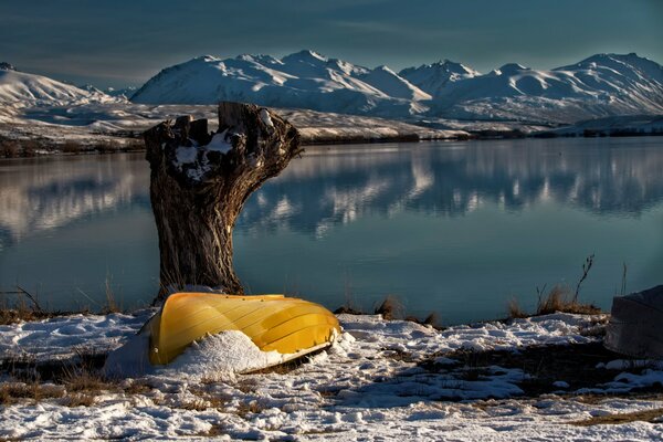 Gelbes Boot am Ufer des Sees. Berge am Horizont