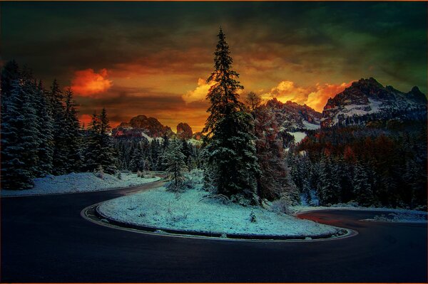 Straße im Hintergrund des Sonnenuntergangs in den schneebedeckten Bergen