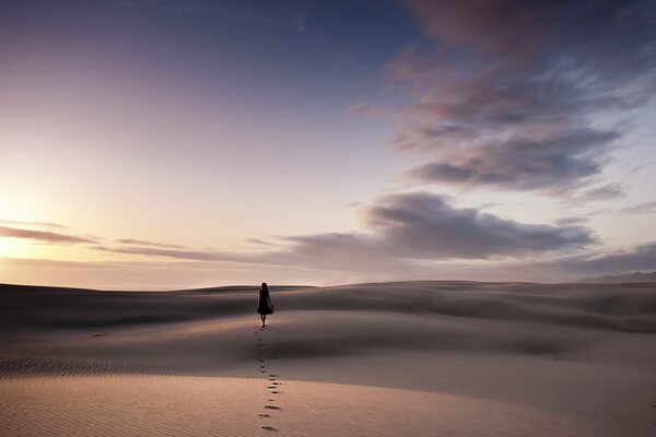 A girl walks on the sand in the desert