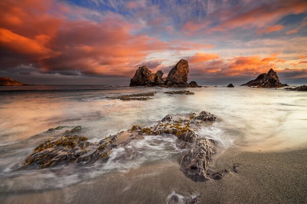 There are rocks on the beach in Italy, you can see the rocks. The clouds in the sky are very beautiful