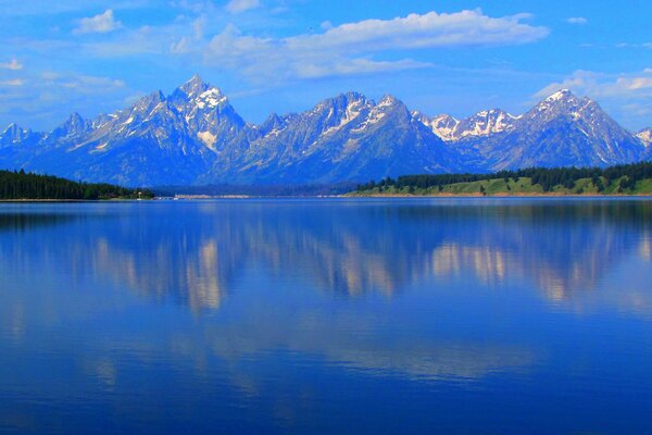 Lake on the background of mountains and forests with a cloudy sky