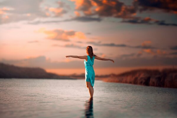 La jeune fille est debout dans l eau. Belle photo de coucher de soleil