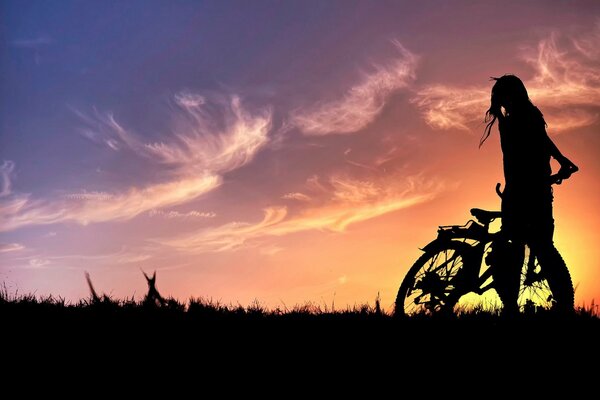 Silhouette of a girl with a bicycle at sunset