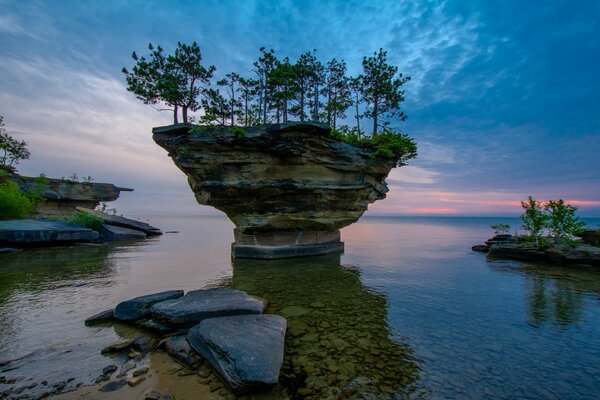 Im Meer steht ein Felsen bei Sonnenuntergang