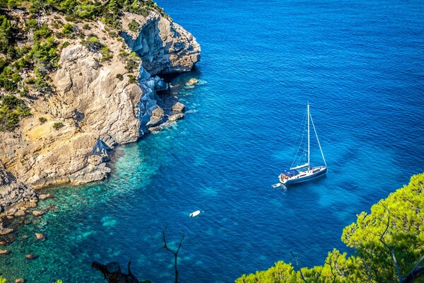 Yacht vor dem Hintergrund der schönen Sträucher und Felsen