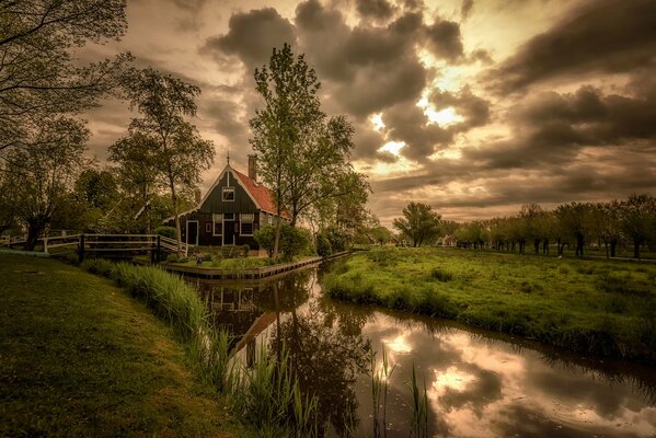 Casa con lago y vegetación bajo las nubes crepusculares