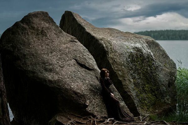 Hermosa chica en el fondo de una enorme piedra