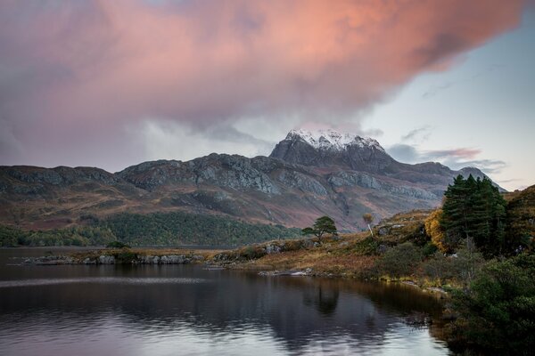 Nubes de tormenta en el fondo de las montañas nevadas del lago y los árboles de otoño