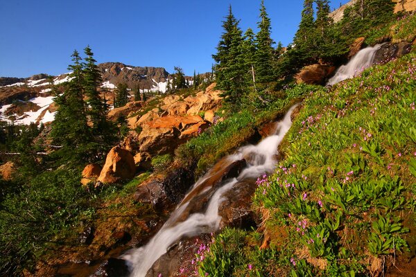 Snow on mountain slopes and waterfall