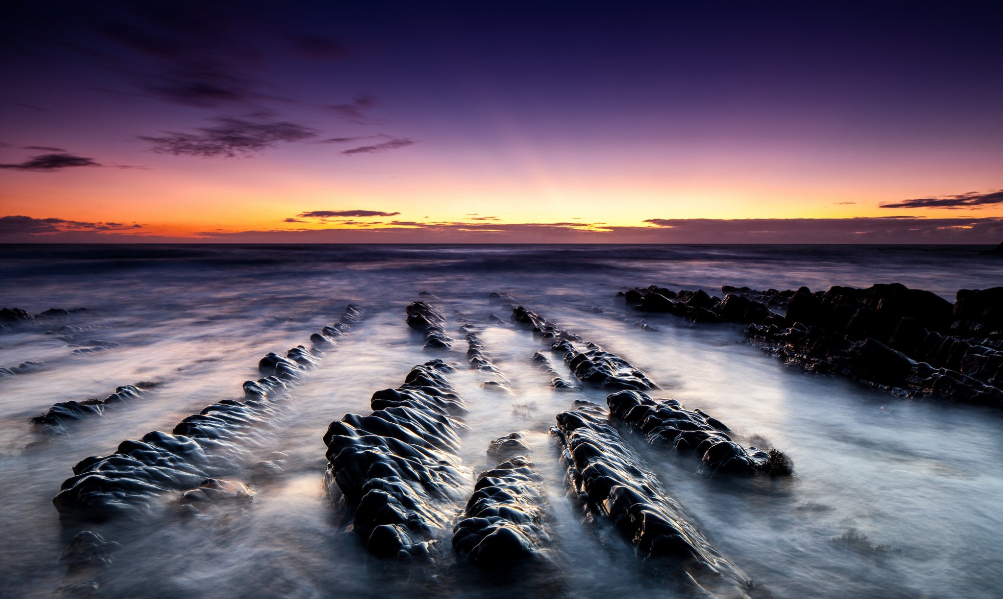 paisaje amanecer océano arena piedras playa rocas