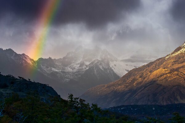 Heller Regenbogen in bewölkten Bergen