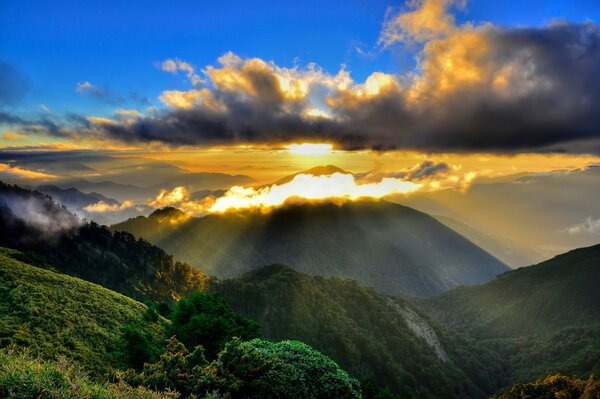 Mañana. Los rayos del sol sobre las montañas en la niebla