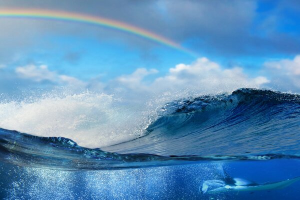 Regenbogen am Himmel über der blauen Meereswelle