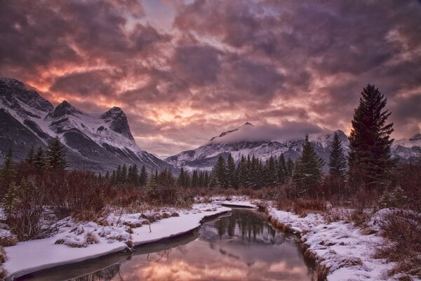 Winter evening in the mountains by the river bank