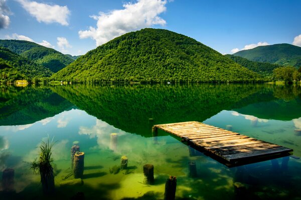 Lugar verde con muelle, montañas, río