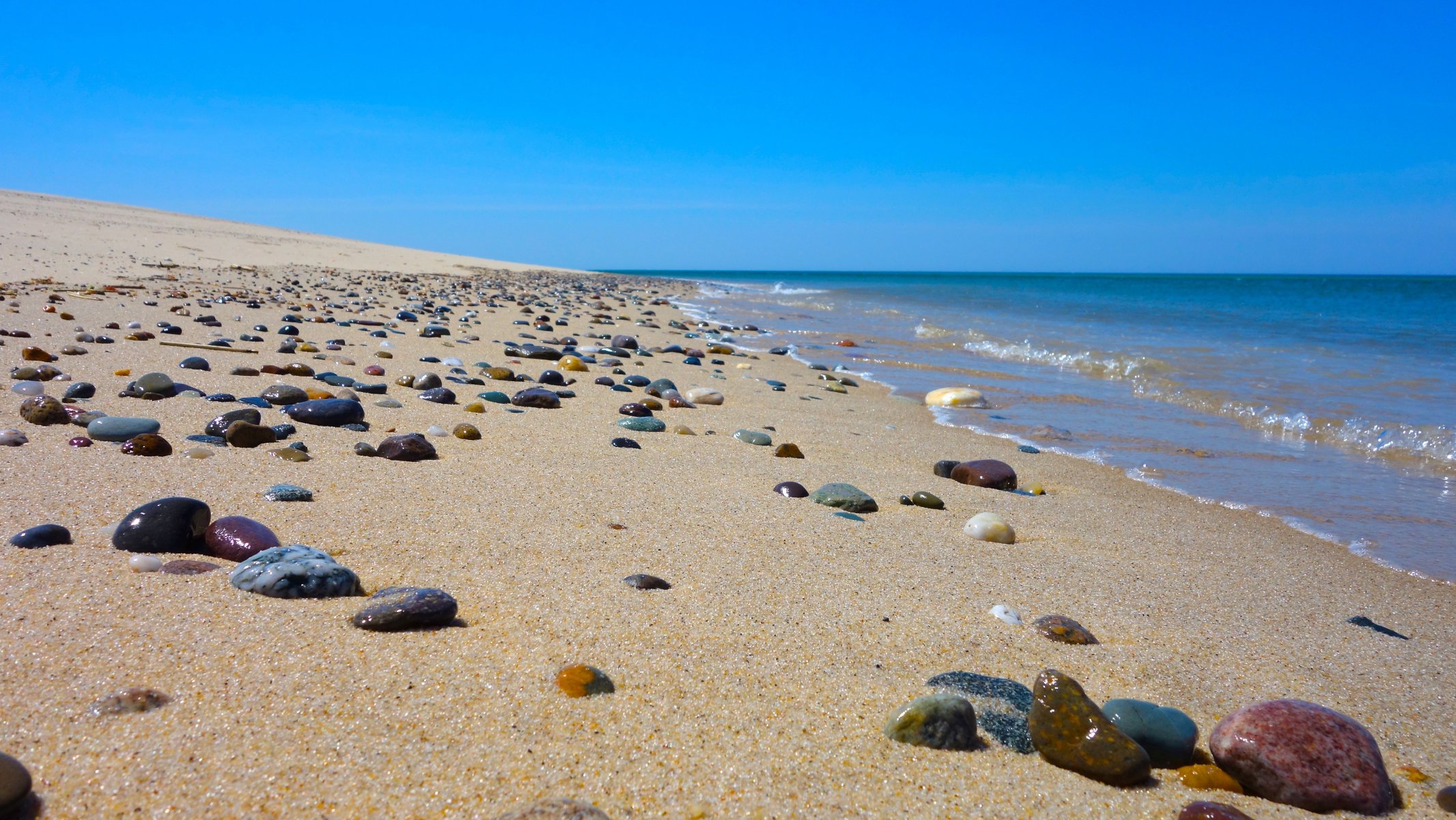 beach sand stones sea waves sky