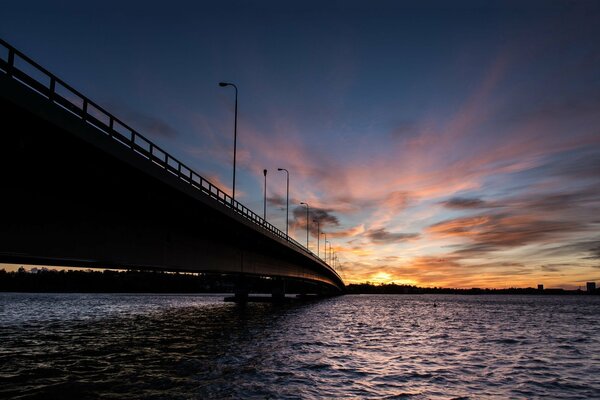 Puesta de sol sobre el puente en el mar