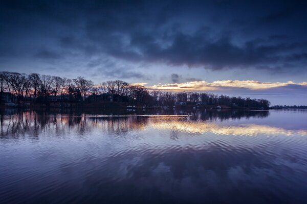 Reflection of the blue clouds and trees in the river