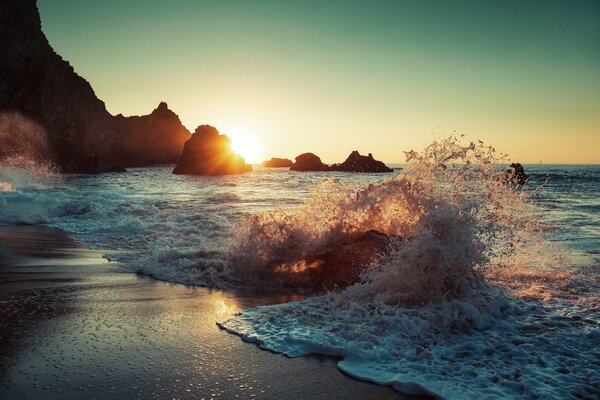 Wellen am Strand bei Sonnenuntergang spritzen