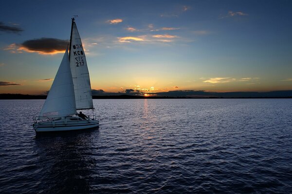 A sailboat sails into the sunset