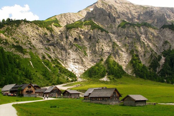 Terreno montañoso con pequeñas casas de madera verdes y un costoso día soleado de verano