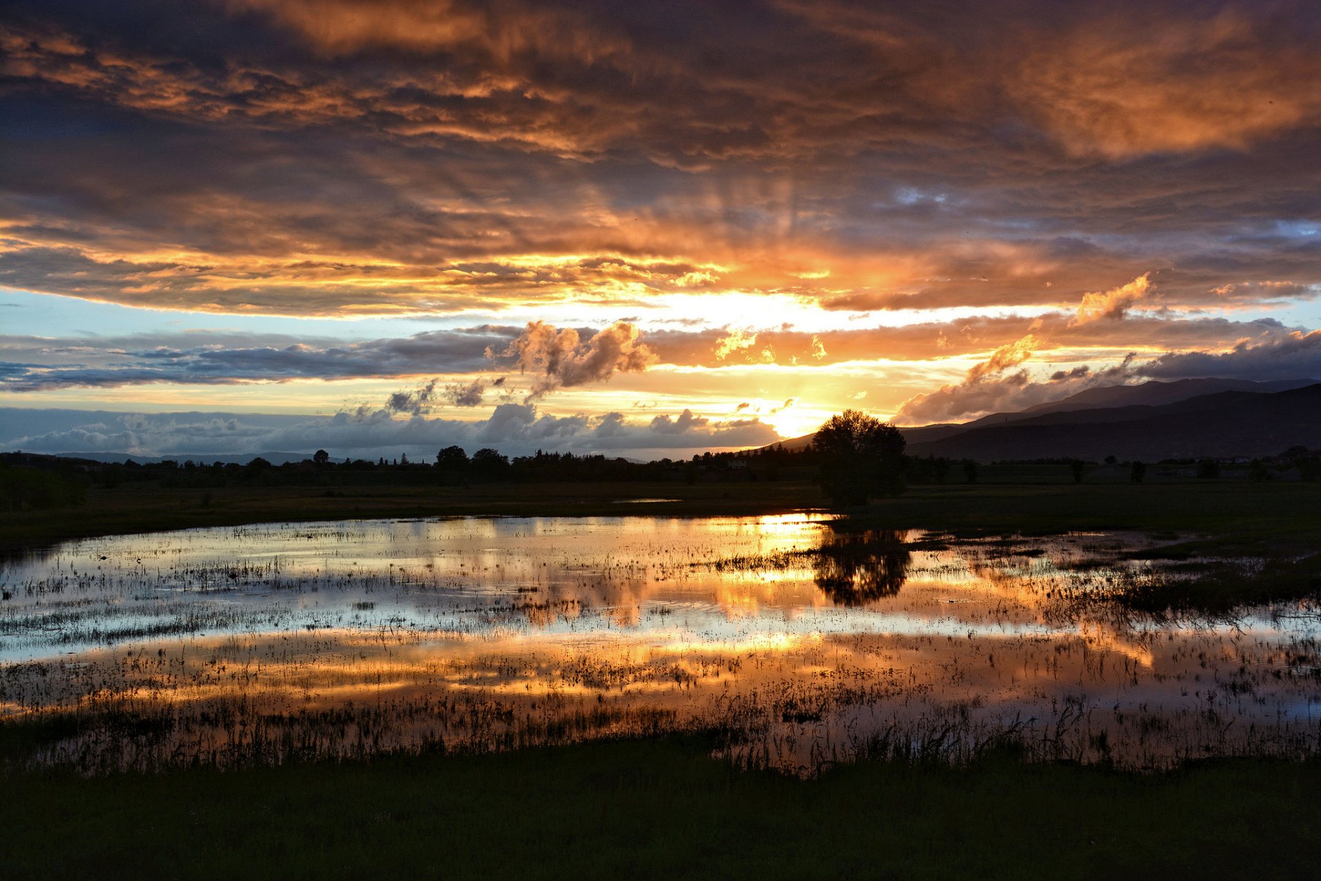 lago pantano tarde puesta de sol nubes sol rayos después de la lluvia