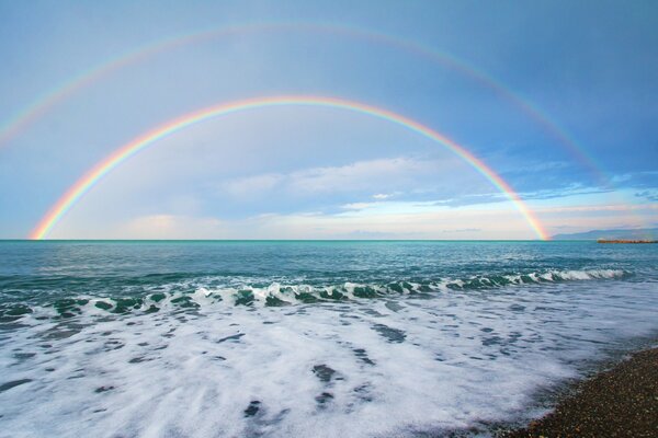 Double rainbow on the background of sea stones