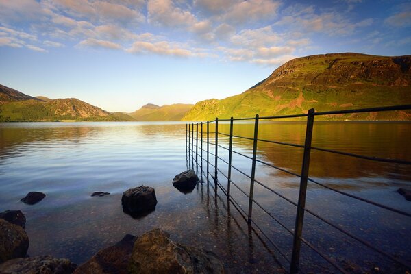 The sea against the background of green hills and a fence