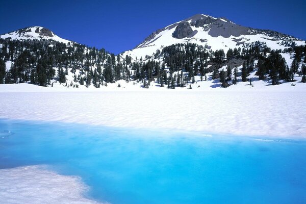 Weißer Schnee, blauer Fluss auf dem Hintergrund der Berge