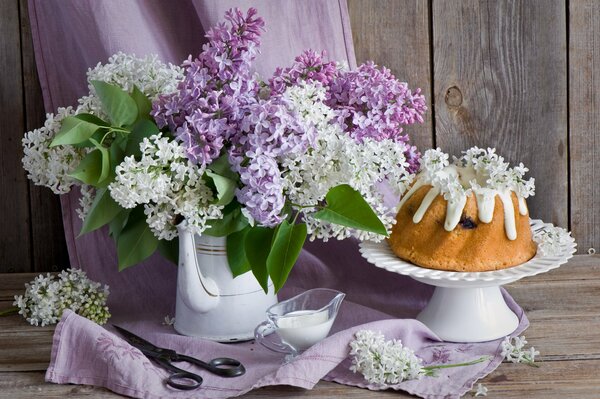 Cupcake and lilac on a wooden background. Still-life