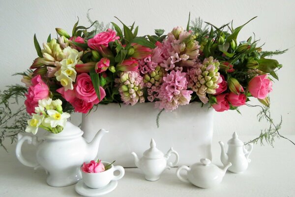 Flowers in a vase with a white tea set