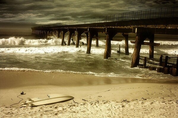 A broken bridge during a storm on a sandy sea beach