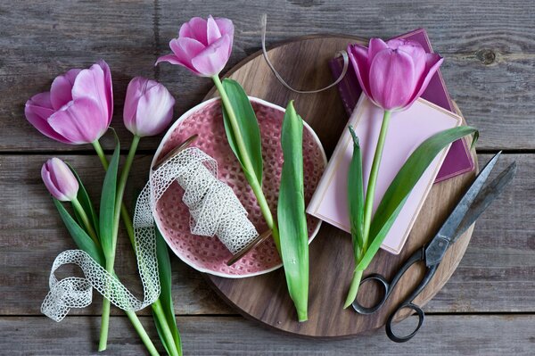 There are tulips, ribbons and scissors on the table